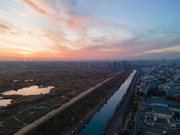 Uitzicht op Boekarest vanaf de drone, waterkanaal, park met groen en meren, meerdere residentiële en commerciële gebouwen, zonsondergang, Roemenië