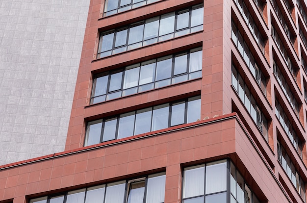 Uitzicht op de grond van modern gebouw gevel met rode betonnen muren, balkon ramen