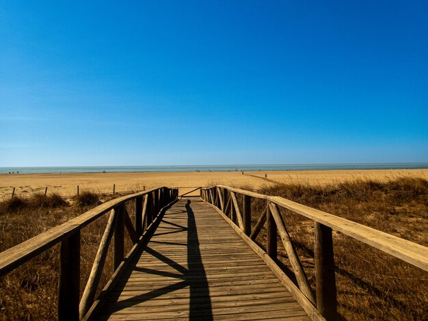 Foto uitzicht op de houten loopbrug die op een zonnige zomerdag naar het strand leidt zomerconcept