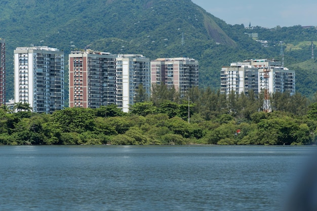 Uitzicht op de lagune van Marapendi met gebouwen op de achtergrond en omringende vegetatie en bomen. Heuvels op de achtergrond. Gelegen nabij Praia da Reserva in Rio de Janeiro.