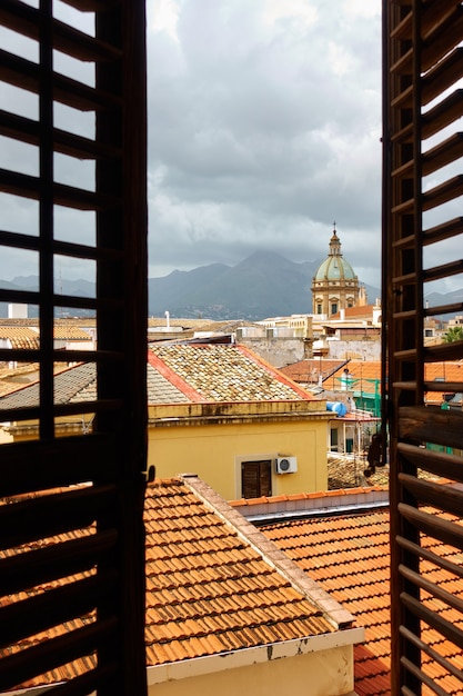 Uitzicht op de oude stad van palermo op sicilië door het open raam met luiken, italië