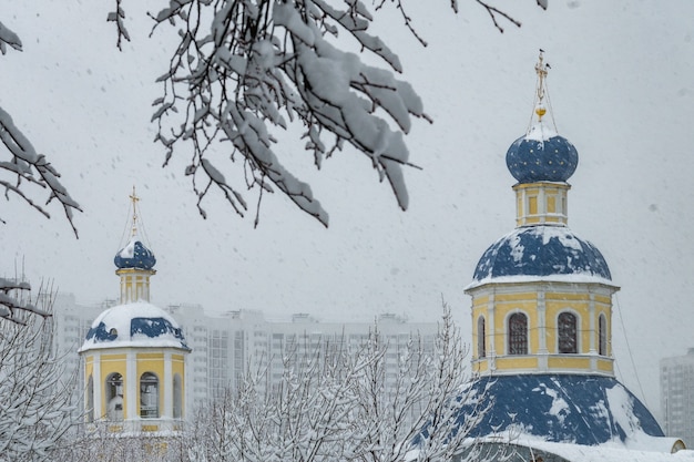 Uitzicht op de Petropavlovskaya-kerk in de herfst in Yasenevo bij sneeuwval.