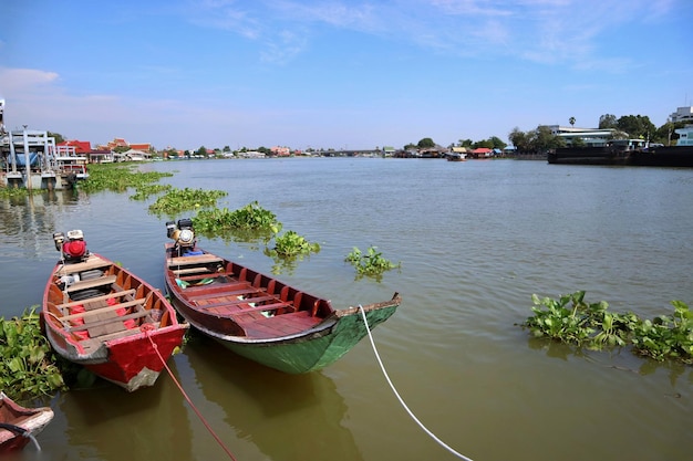 Uitzicht op de rivierzijde met twee lange staartboten in Thaise stijl en de tempelachtergrond in Bangkok Thailand