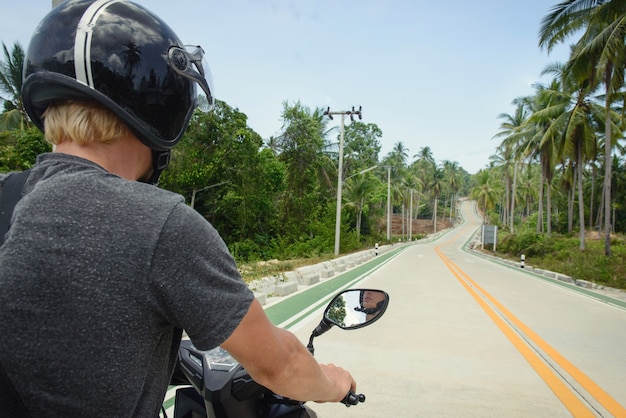 Uitzicht op de snelweg vanaf het punt van de bestuurder van de scooter. Achterkant van de toerist op de weg in Thailand, Phangan.