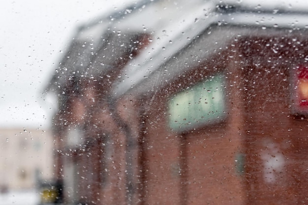 Uitzicht op de stad door nat glas een winterlandschap