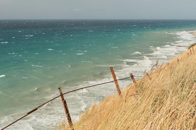 Uitzicht op de stormachtige zee vanaf een klif begroeid met droog gras Zeezicht achtergrond met vrije ruimte