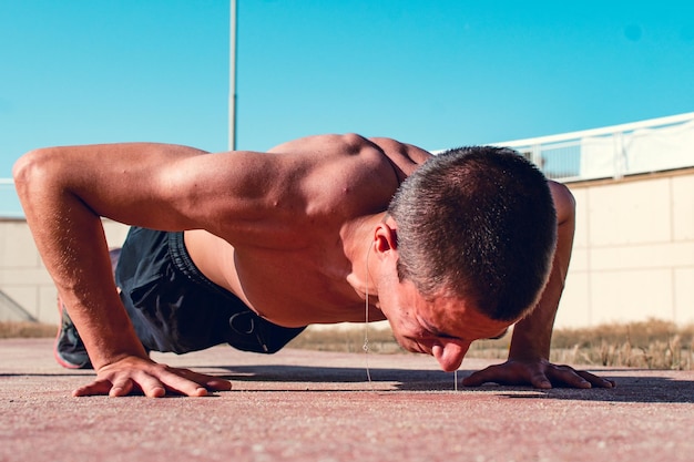 Uitzicht op de vloer van een jonge blanke jongen die een push-up op de vloer doet en lijdt