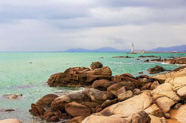 Foto uitzicht op de vuurtoren in de zee bij de rotsachtige kust hemelse grotten park sanya china