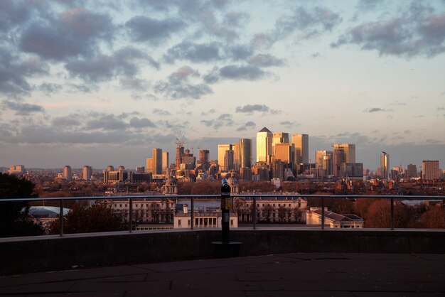 Uitzicht op de wolkenkrabbers van Londen vanaf een uitkijkpunt op Greenwich bij zonsondergang en kijker.