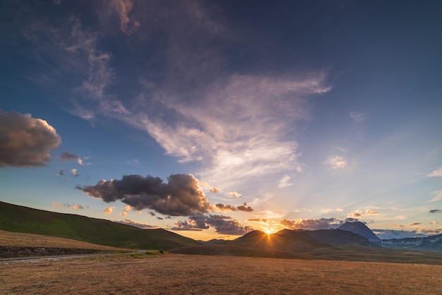 Uitzicht op de zonsondergang op rotsachtige bergen, hooglanden en weilanden. Campo Imperatore, Gran Sasso, Apennijnen, Italië. Kleurrijke wolken in de lucht op dramatische bergrug.