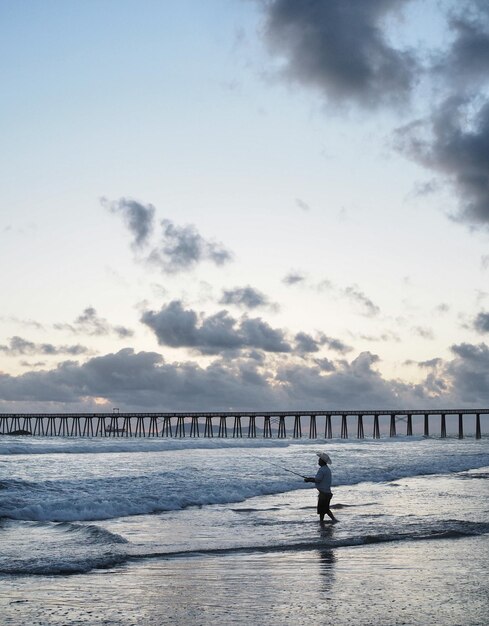 Uitzicht op een man die op het strand aan het vissen is
