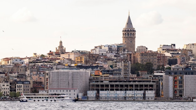 Uitzicht op een wijk met residentiële gebouwen en de Galata-toren in Istanbul, Bosporus met bewegende boot op de voorgrond, Turkije