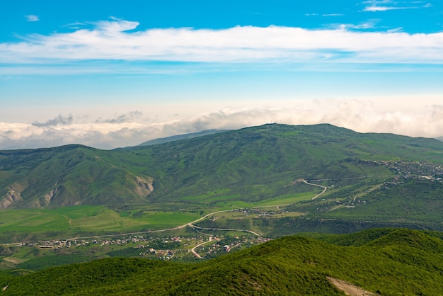 Uitzicht op groene bergen en dorpjes in de vallei. Groothoekpanorama