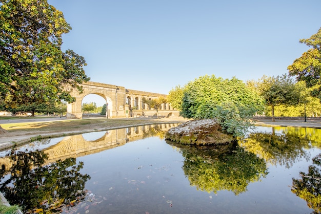 Uitzicht op het aquaduct van heilige clement in de peyrou-tuin met waterreflectie tijdens het ochtendlicht in de stad montpellier in zuid-frankrijk