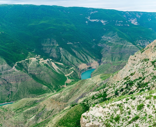 Uitzicht op het berglandschap van een enorme kloof met rotsachtige groene hellingen en een blauwe rivier onderaan