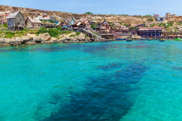 Uitzicht op het beroemde dorp Popeye met kleurrijke houten huizen en de Golf van Malta.