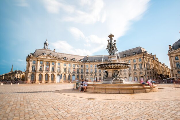 Foto uitzicht op het beroemde plein la bourse met fontein in de stad bordeaux, frankrijk. beeldtechniek met lange belichtingstijden met beweging wazige mensen en wolken