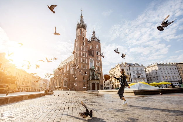 Uitzicht op het centrale plein en de beroemde st. Marys basiliek met duiven die vliegen tijdens de zonsopgang in Krakau, Polen