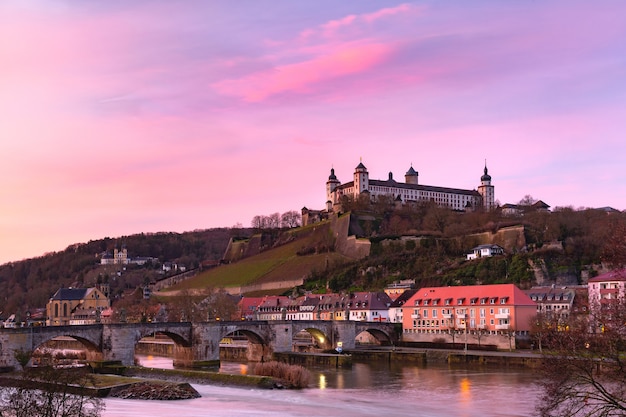 Uitzicht op het fort Marienberg en de oude hoofdbrug, Alte Mainbrucke in Würzburg bij roze zonsondergang, Beieren, Duitsland