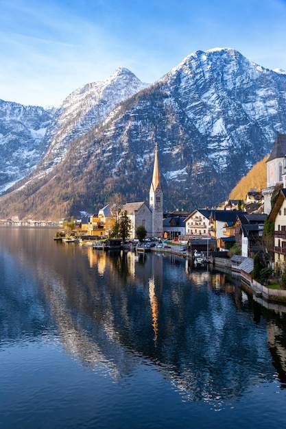 Uitzicht op het prachtige Hallstatt-meer en de beroemde kerk tijdens de ochtendzonsopgang in het vroege voorjaar met bergketens bedekt met wat sneeuw