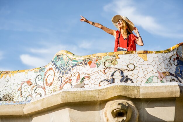 Uitzicht op het prachtige terras versierd met mozaïek met gelukkige vrouwelijke toerist in Guell park in Barcelona