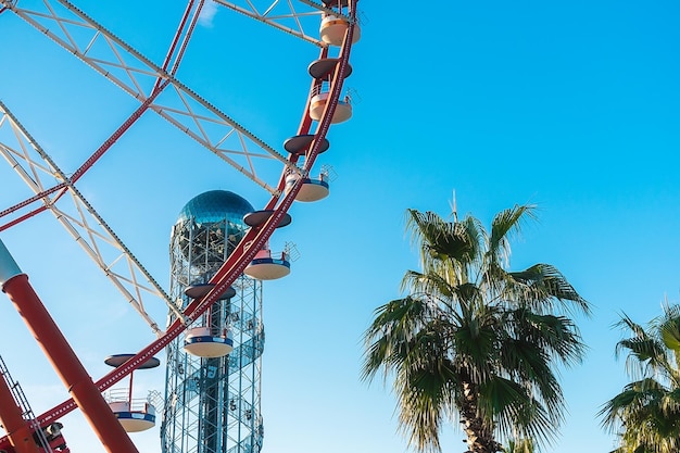 Foto uitzicht op het reuzenwiel en de alphabet tower tegen een achtergrond van blauwe lucht tussen palmbomen