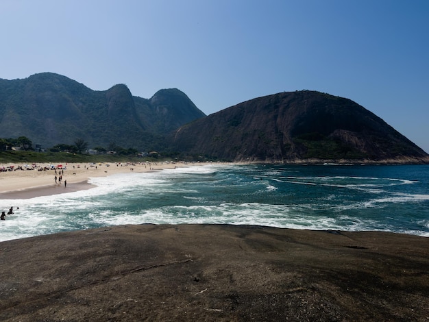 Uitzicht op itacoatiara strand in niteroi in rio de janeiro brazilië met zijn prachtige heuvels rond het strand grote golven in een zonnige zomerdag