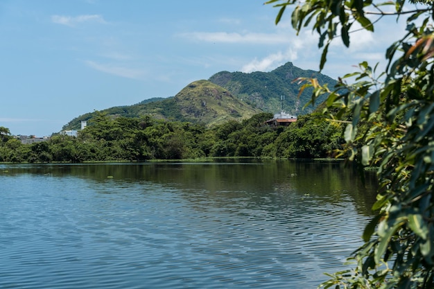 Uitzicht op Lagoinha das Taxa in Parque Chico Mendes in Rio de Janeiro, Brazilië. Sommige gebouwen, vegetatie en heuvels op de achtergrond. Zonnige dag met blauwe lucht.