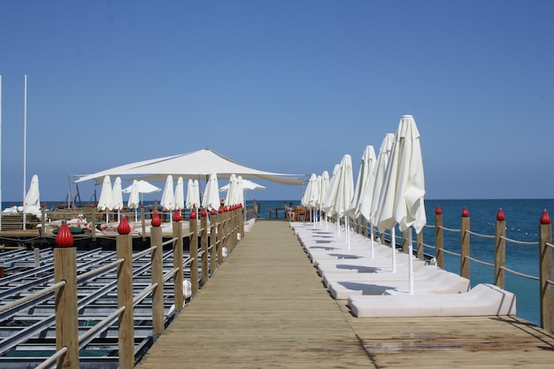 Uitzicht op lange pier met witte chaiselongues en parasols