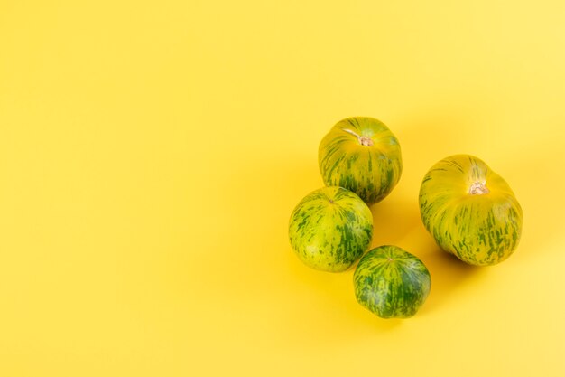 Uitzicht op prachtige groene gestreepte tomaten op gele achtergrond