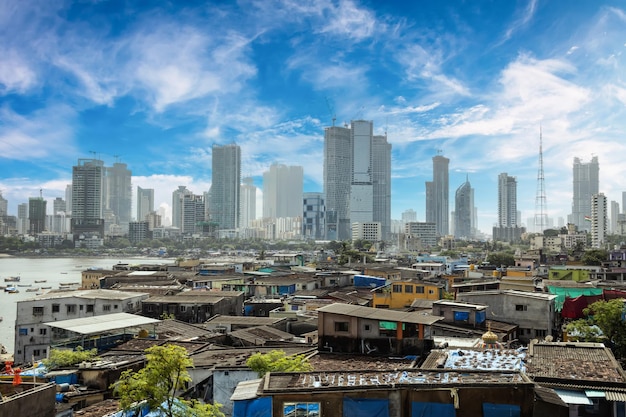 Uitzicht op sloppenwijken aan de kust van Mumbai, India tegen de achtergrond van wolkenkrabbers in aanbouw