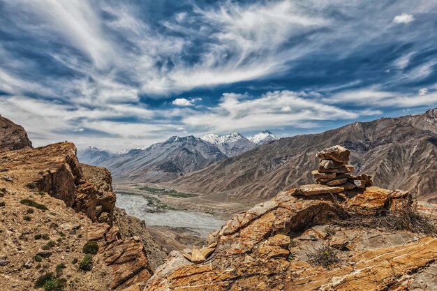 Uitzicht op vallei in de Himalaya met stenen steenhoop op klif