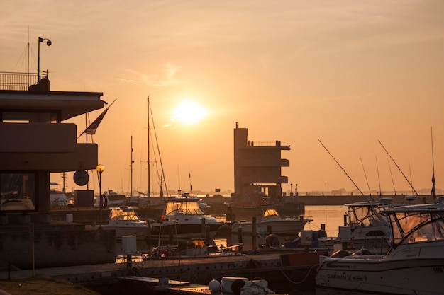 Uitzicht op verschillende boten afgemeerd aan de grote haven van Albarella in Italië, verlicht door de warme kleuren van de dageraad