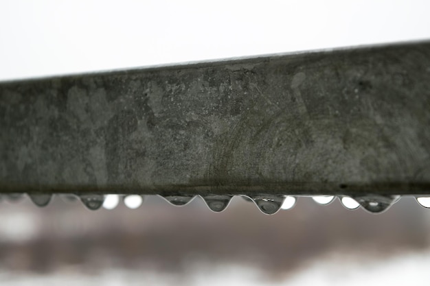 Uitzicht op waterdruppels die op een regenachtige dag aan een metalen reling hangen