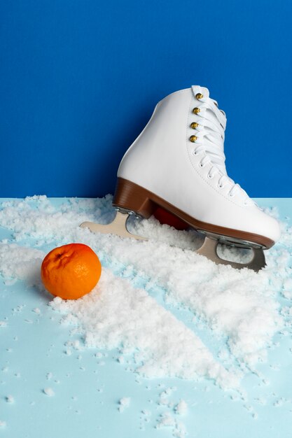 Uitzicht op witte schaatsen met mandarijnen en sneeuw