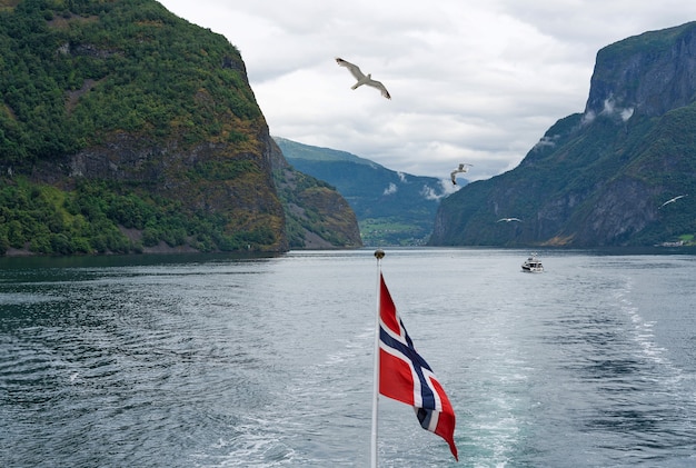 Foto uitzicht op zee op de bergen van sognefjord en neroyfjord met noorse vlag