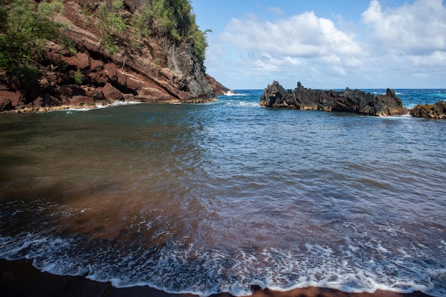 Uitzicht op zee strand met golven en rotsachtige kust rode zandstrand Maui in in Hawaii