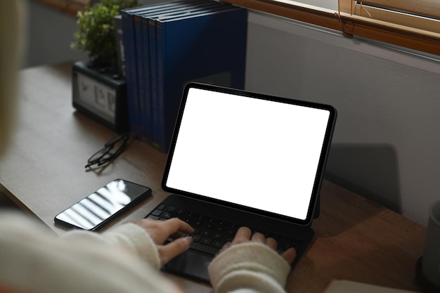 Uitzicht over de schouder van een jonge vrouw met behulp van computertablet