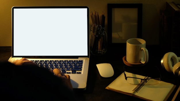 Uitzicht over man schouder handen typen op het toetsenbord van de laptopcomputer aan het bureau