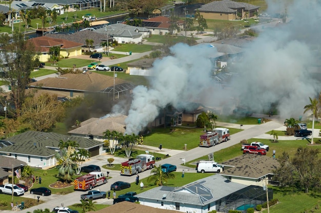 Uitzicht van bovenaf op brandend privéhuis in brand en brandweerlieden die vlammen blussen na kortsluiting veroorzaakt door ontsteken van dak beschadigd door orkaan Ian wind Home ramp in een buitenwijk van Florida