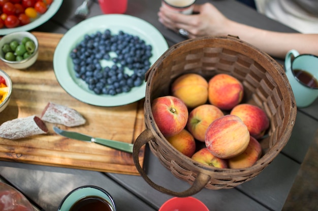 Uitzicht van bovenaf op een picknicktafel met een mand met verse perziken schotel van bosbessen een salade lunch buiten