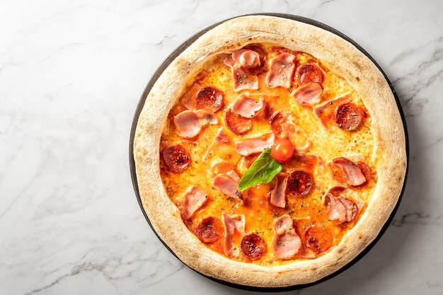 Uitzicht van bovenaf op heerlijke pizza met salami, ham en kaas op witte marmeren tafel