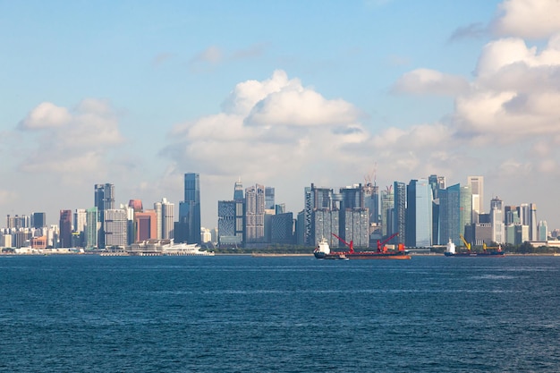 Uitzicht van de zee naar Singapore met hoge gebouwen en de kust en transportschepen aan het anker