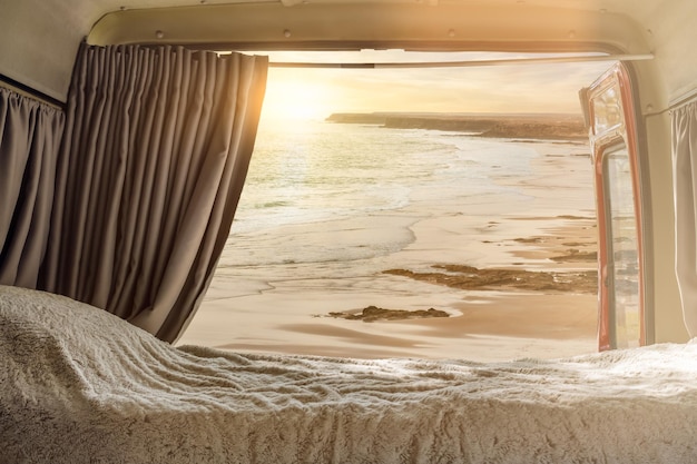Uitzicht vanaf de binnenkant van een camper aangepast voor de zonsondergang op het strand Vrijheidsconcept
