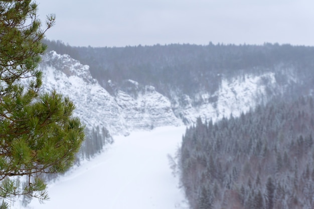 Uitzicht vanaf de klif naar de besneeuwde beboste vallei van de winter bevroren rivier