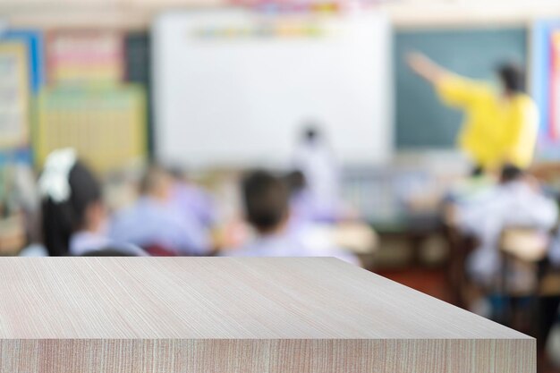 Uitzicht vanaf houten tafel in leeg klaslokaal blur kinderen en leraar in het klaslokaal