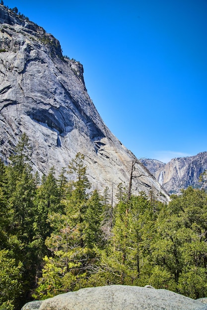 Uitzicht vanaf rotsblok van Yosemite-vallei vol met pijnbomen en waterval in de verte