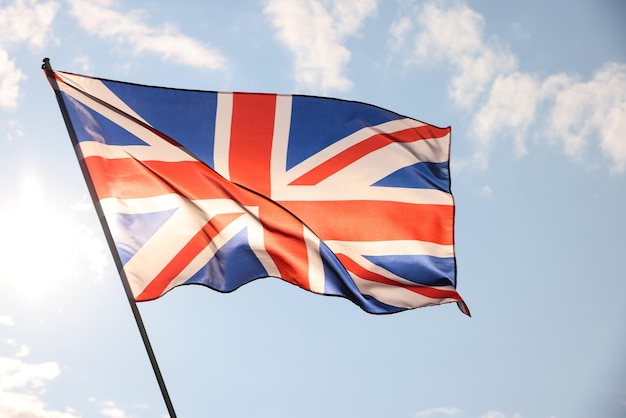 Uk great britain flag waving in cloudy blue sky