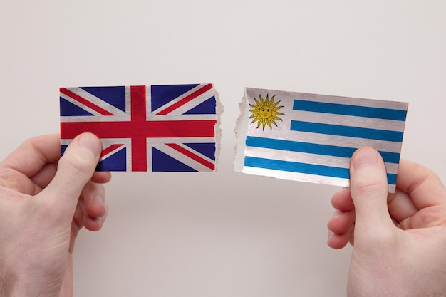 UK and Uruguay paper flags ripped apart political relationship concept