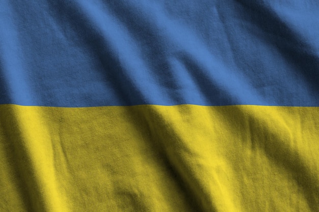 Ukraine flag with big folds waving close up under the studio light indoors The official symbols and colors in banner